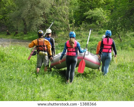 Rafting team carrying the boat on the river-bank