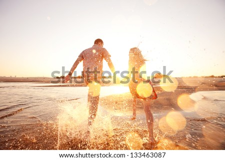 happy couple running on the beach - stock photo