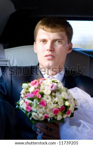 groom with flower bouquet in the car