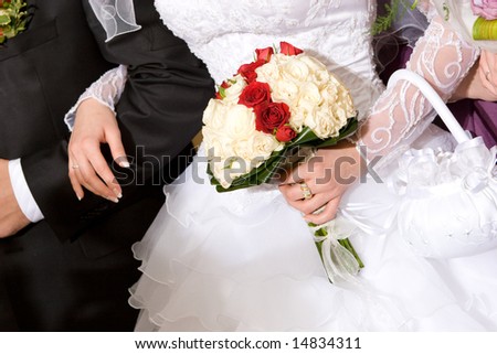 bouquet of red and white roses in the hands of newly married couple