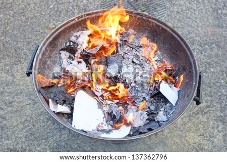 Fire Pit with burning papers and letters, flames, smoke and ash.
