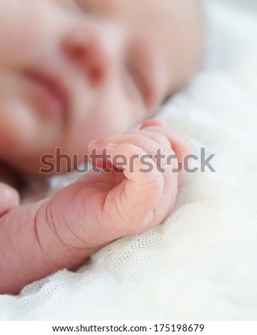 Newborn baby with tiny hand in focus.