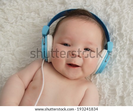 Cute baby boy with blue headphones on ears