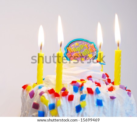 Decorated birthday cake with lit candles and candy sprinkles.  Note:  Focus on right side.
