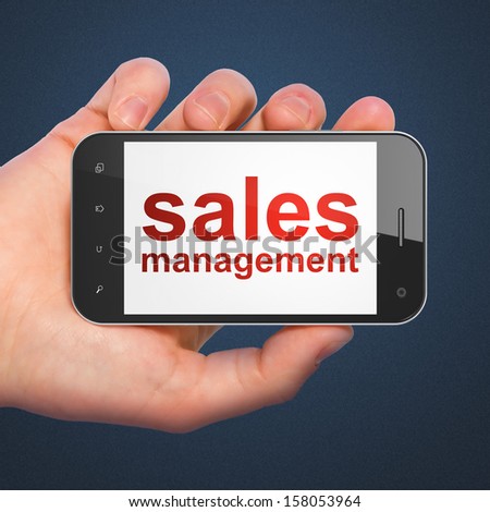 Marketing concept: hand holding smartphone with word Sales Management on display. Mobile smart phone in hand on Blue background, 3d render