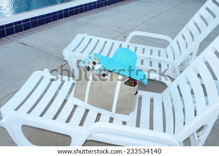 White deck chairs by a swimming pool with pool accessories