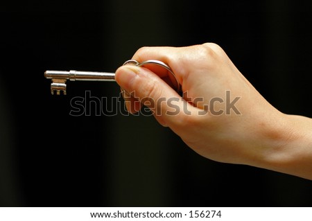 Outstretched hand holding a key, on an isolated black background