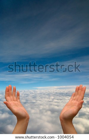 Hands reaching to heaven, on a cloud-filled blue sky background