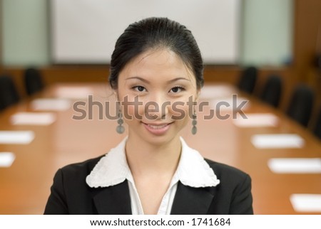 Asian lady in business attire in front of conference room
