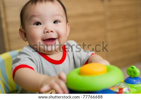 6 month old Asian baby girl smiling excitedly while sitting in a walker