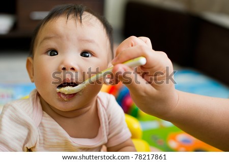 Six month old South East Asian Chinese baby girl being spoon fed