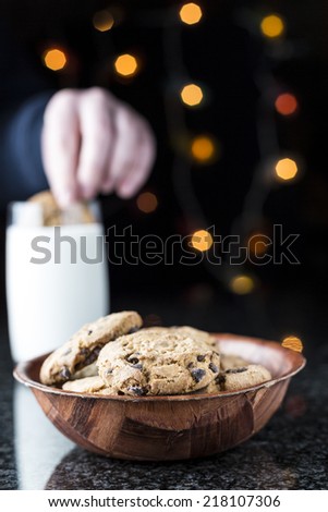 Chocolate chip cookies and milk on a granite table with lights on the background