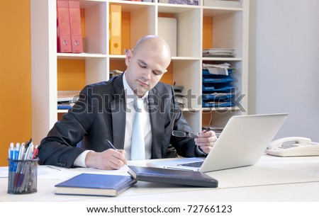 Businessman writing financial details in his fancy bright office.