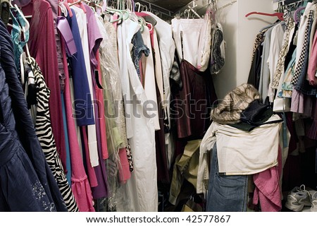 Messy unorganized closet full of hanging clothes