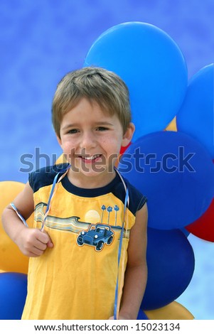 a happy little boy holds a bundle of balloons