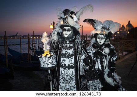 VENICE,ITALY-FEB.17 : Masked couple wearing carnival costume and posing along Saint Mark waterfront on February 17, 2012 in Venice, Italy. In 2012 the Carnival was held between 11-21 February.