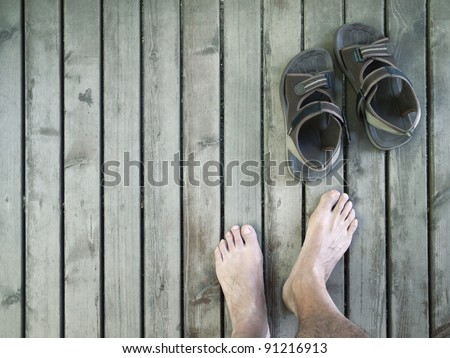 Male feet and sandals on plank floor