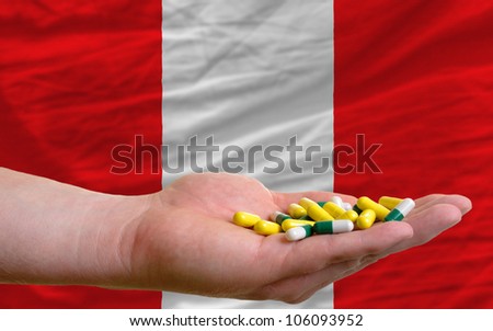 man holding capsules in front of complete wavy national flag of peru symbolizing health, medicine, cure, vitamines and healthy life