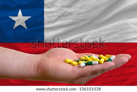 man holding capsules in front of complete wavy national flag of chile symbolizing health, medicine, cure, vitamins and healthy life