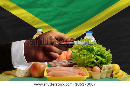 man stretching out credit card to buy food in front of complete wavy national flag of jamaica