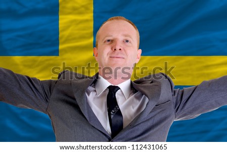 joyful investor spreading arms after good business investment in sweden, in front of flag