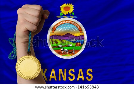 Winner holding gold medal for sport and flag of us state of kansas