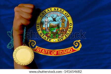 Winner holding gold medal for sport and flag of us state of idaho