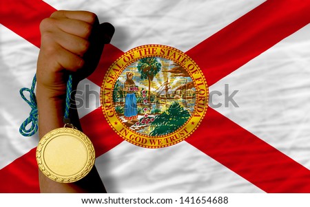 Winner holding gold medal for sport and flag of us state of florida