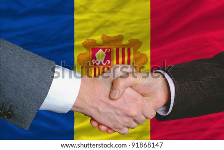 two businessmen shaking hands after good business investment  agreement in andorra, in front of flag