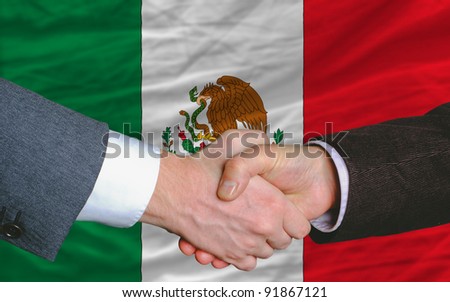two businessmen shaking hands after good business investment  agreement in mexico, in front of flag