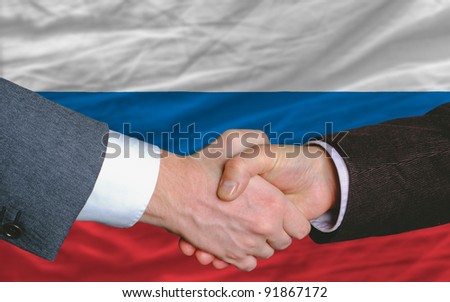 two businessmen shaking hands after good business investment  agreement in russia, in front of flag