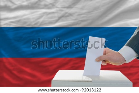 man putting ballot in a box during elections in russia