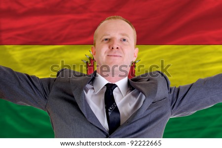 joyful investor spreading arms after good business investment in bolivia, in front of flag