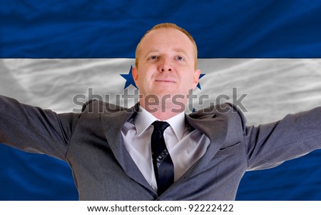 joyful investor spreading arms after good business investment in honduras, in front of flag