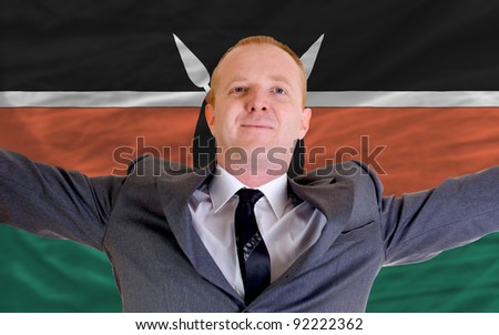 joyful investor spreading arms after good business investment in kenya, in front of flag