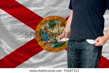 poor man showing empty pockets in front of florida flag