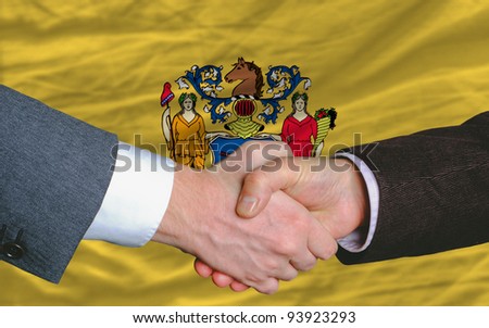 two businessmen shaking hands after good business investment agreement in front US state flag of new jersey