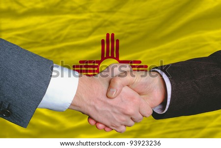 two businessmen shaking hands after good business investment agreement in front US state flag of new mexico