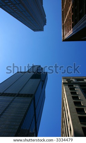 Buildings from different ages seen from below at sunset against blue sky, vertical
