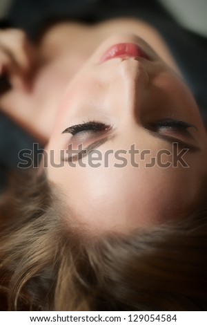 Attractive female brunet  lying down, head back and arched, focus on the eyelashes