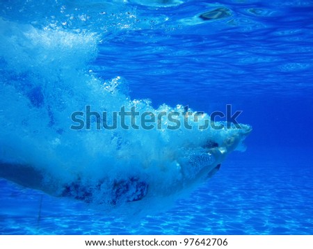 Underwater shot of a young man who dives head first into the pool
