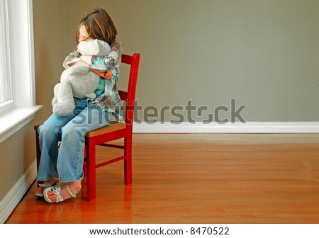 Young girl hugging stuffed animal looking out of window
