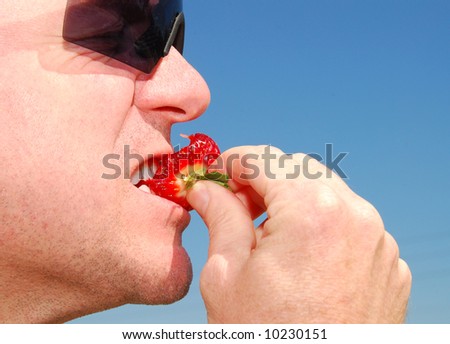 Man Eating Strawberry Outside