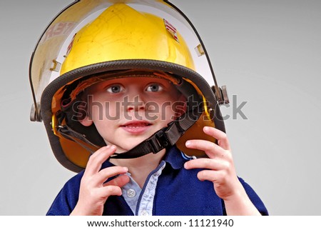 Cute young toddler boy wearing real fireman\'s helmet