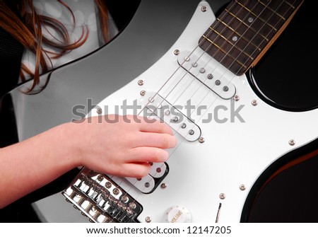 Girl playing electric guitar with hand on strings