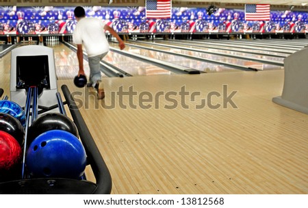 Stacked bowling balls at festive lanes with bowler in distance
