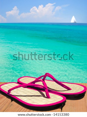 Pink flip flop sandals on dock overlooking gorgeous ocean with sailboat in distance