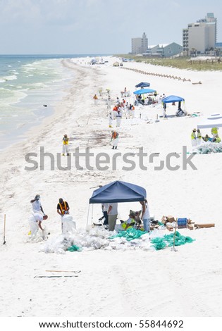 PENSACOLA BEACH - JUNE 23: BP oil workers attempt to clean oil covered sand on June 23, 2010 in Pensacola Beach, FL.