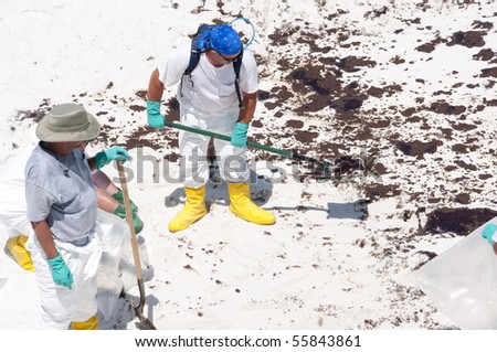 PENSACOLA BEACH - JUNE 23: A BP oil workers attempt to clean oil covered sand on June 23, 2010 in Pensacola Beach, FL.