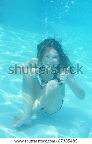 Young girl underwater giving thumbs-up sign